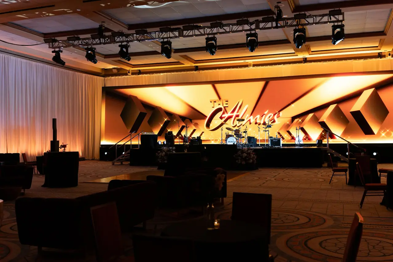 Gala stage with angled amber and white LED panels and a lit script logo