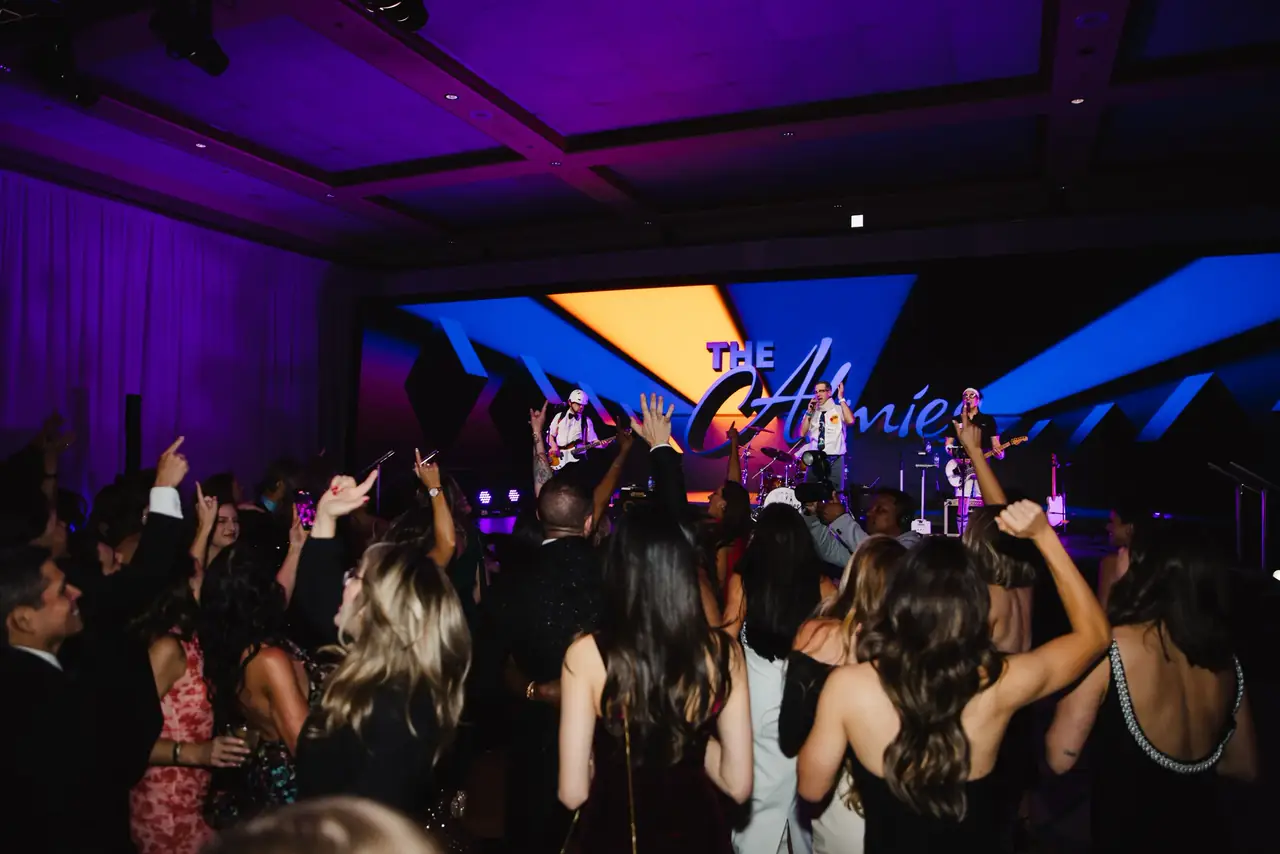 Alma Academy night session: crowd on its feet in front of a stage framed by angled LED and purple light