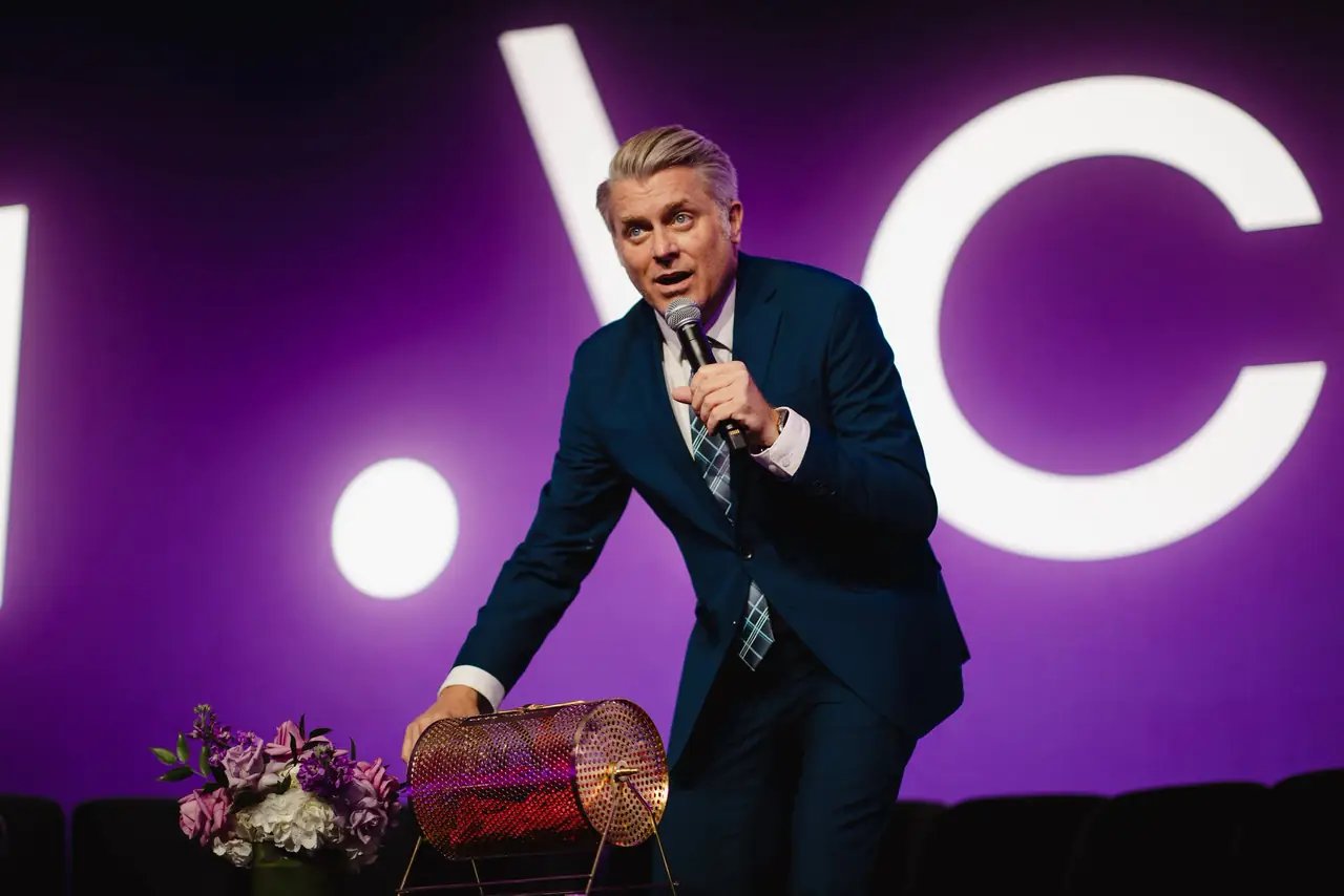 Speaker on stage in front of a large purple LED backdrop
