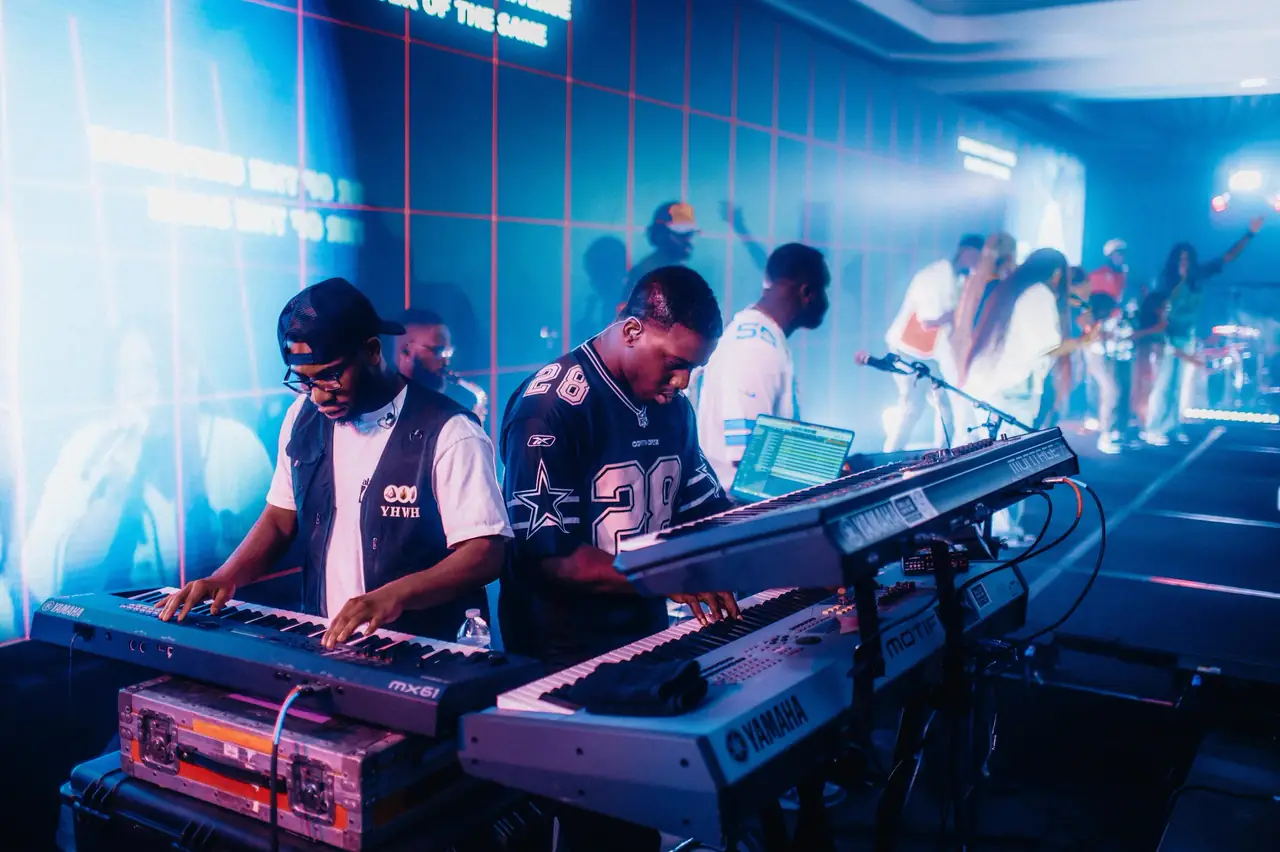 Keyboard players on stage in front of a blue LED wall