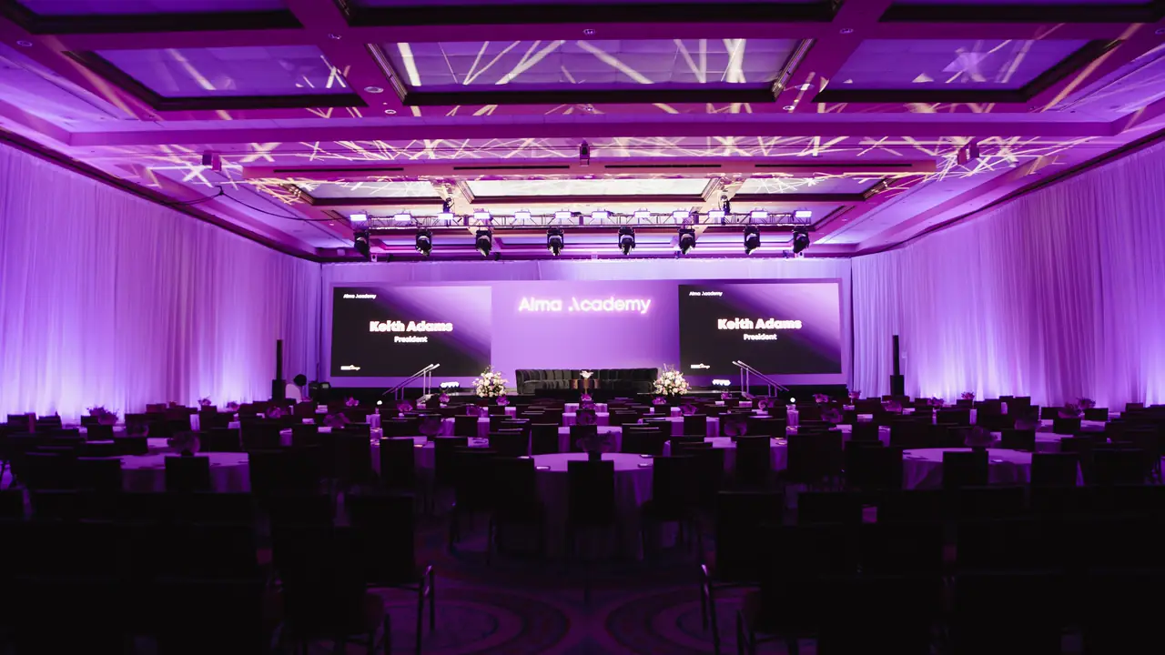 The same ballroom from the back on the day: Alma Academy on the centre screen, side screens, purple drape