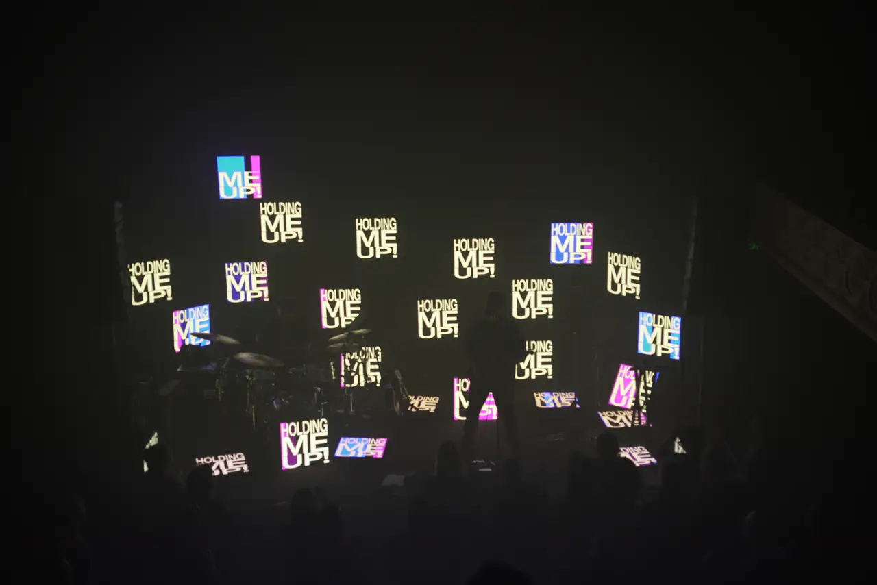 Wide view of the stage: LED panels showing lyrics across the back of the stage