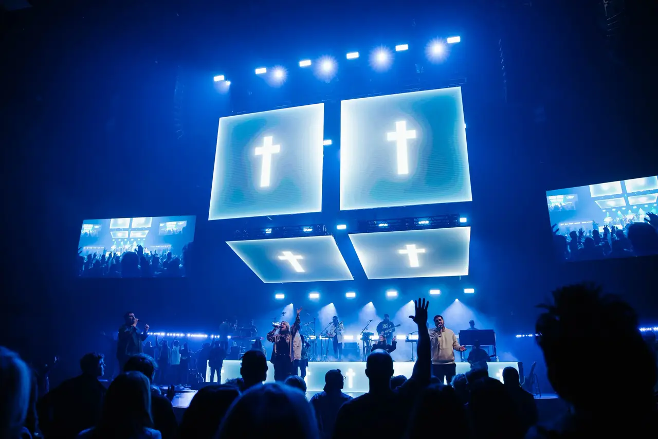 Suspended LED cubes showing crosses above the Victory Conference stage, with side screens and the crowd below