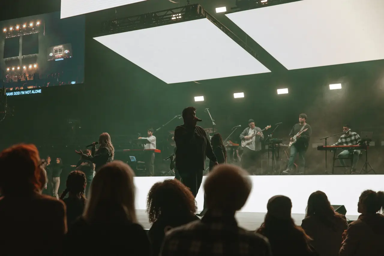 Session at Victory Church with a white stage, suspended panels and the band
