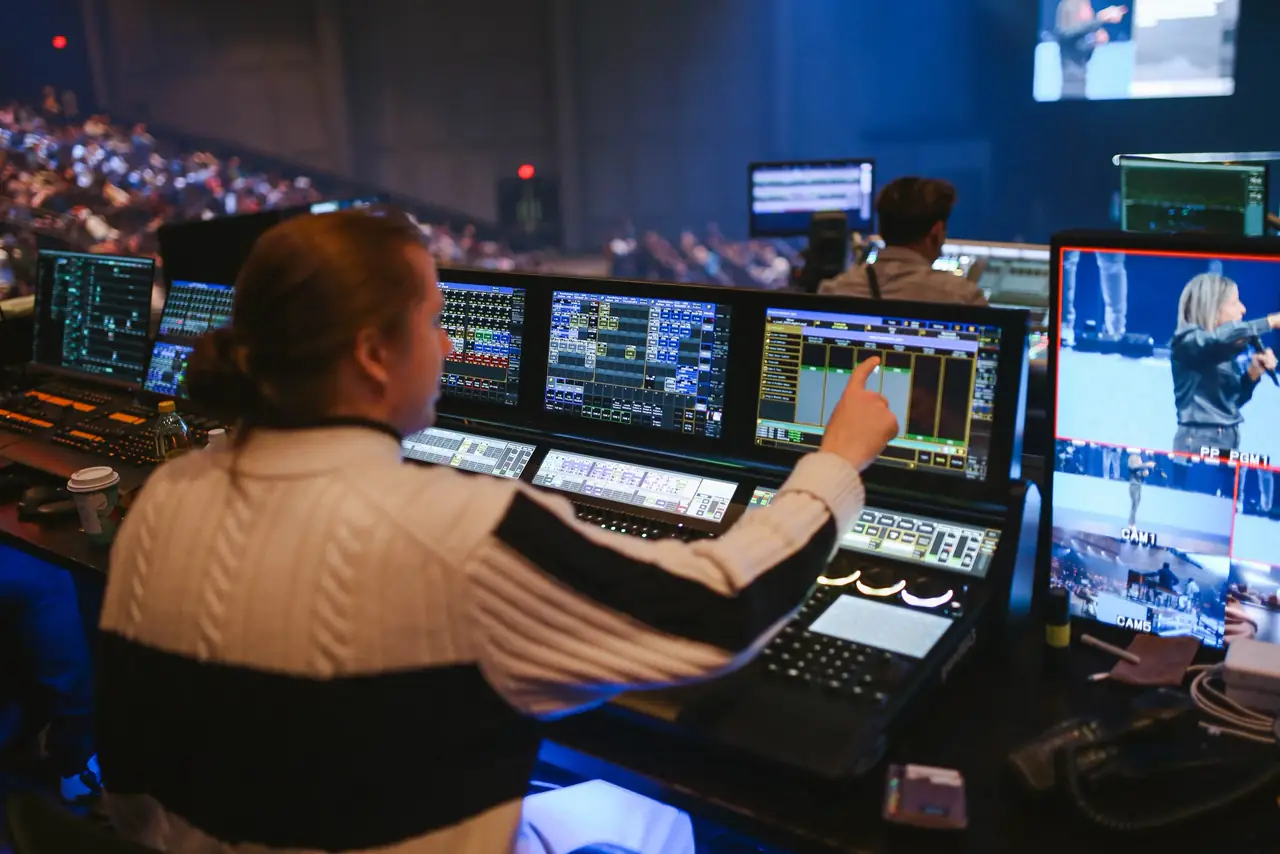 Operator at a video switcher and multiview monitors running a Victory Conference session