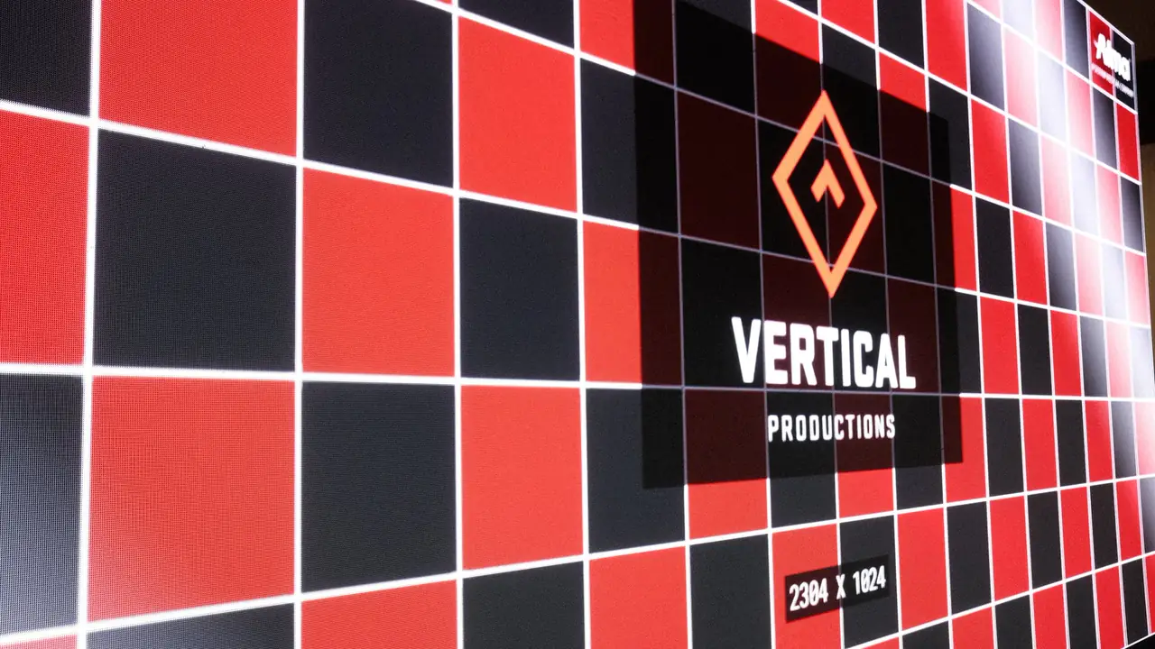 Vertical Productions LED wall showing a red and black test grid with the VP logo